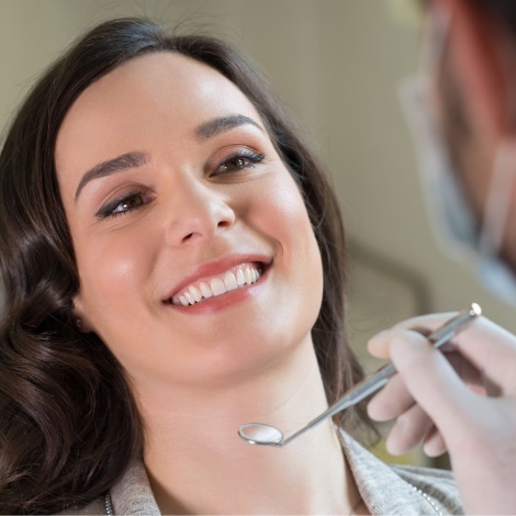 Smiling in woman in dental chair getting her teeth cleaned by dentist.